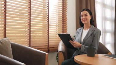 Mutlu ve gülümseyen kadın psikolog psikiyatri ofisinde ya da terapi odasında pano tutuyor. Arkadaş canlısı ve profesyonel ruh sağlığı danışmanı ya da terapisti. Blithe