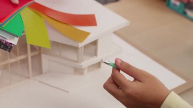 Mimari ekipman kullanarak yavaş çekim ev tasarımcısı bir plan çizerken, iç mimari tasarımcı da müşterilerin talebine göre renk örneklerinden uygun renkler seçiyor. Değiştirilmiş