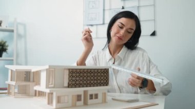 Profesyonel mühendis mimarın üçgen ölçekli ölçü evi modelini kullanarak modern ofisteki yapı uzunluğunu not alarak yakınlaşması. İş tasarımı. Tertemiz..