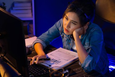 Bitkin düşmüş, genç, güzel Asyalı yaratıcı hisler, bilgisayardan e-posta beklemek için bekliyor. Projenin yaratıcısı sosyal medyanın veri tablosunu gece vakti neon ofiste karşılaştırıyoruz. Taktik.