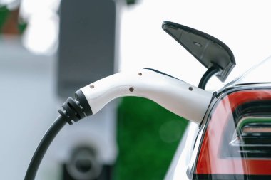 Elektrikli araç portuna bağlı EV şarj prizi kolu şarj istasyonundan şarj oluyor. Modern tasarlanmış EV araba ve daha iyi bir gelecek konsepti için temiz enerji sürdürülebilirliği. Eşzamanlama