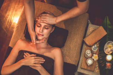 Beyaz kadın stres önleyici kafa masajı yapmaktan ve lüks otel veya otelde sıcak mum ışığında yüz güzelliği eğlencesi yapmaktan zevk alıyor. Sessiz.