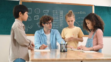 Zeki öğretmen, çeşitli çocuklar sınıf çalışması yapmak için birlikte çalışırken farklı çocukların zihin haritası çizdiği fikri açıklıyor. Çekici eğitmen öğretmek ve çalışmak hakkında konuşmak. Pedagoji.