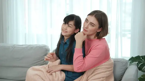 stock image Happy girl sitting on caucasian mothers lap while mom telling fairytale story. Mother pointing and giving warmly hug while daughter looking and smiling at home. Family spend time together. Pedagogy.