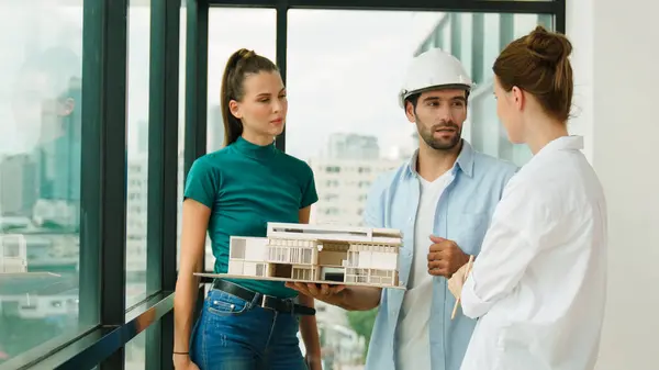 Skilled engineer holds house model and explain about house construction to skilled manager. Group of interior designer inspect architectural model. Working together, Civil engineering. Tracery