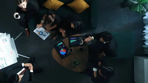 Top down view of business people listen businessman present idea while making decision. Group of diverse team making a decision to invest start up project while hold tablet display graph. Directorate.