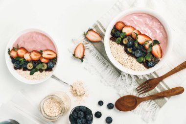 Meyvelerin sunduğu yoğurt malzemelerini çilek, yulaf, kuru üzüm ve nane şekeriyle süslenmiş Chia tohumu ile beyaza boyarız. Pembe arka plan. Sağlıklı süt ürünleri seti. Bireysel.