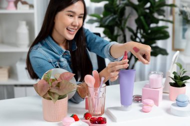 Genç, güzel Asyalı kozmetik makyaj ruju matte pastel rengini modern odadaki sosyal medyada kol testi tanıtımında en çok satanlar listesinde gösteriyor. Taktik.