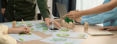 Yenilenebilir enerji ve eko kenti temsil eden ahşap bloğu temsil eden yel değirmeni modeli, çevreci dökümanların dağıtıldığı yeşil iş toplantısı masasına yerleştirildi. Ön manzara. Tanımlama.