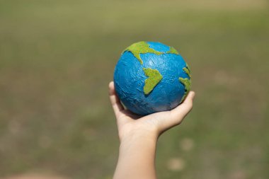 Dünya gezegenini ESG ilkesi ve çevre dostu enerjisiyle daha parlak bir gelecek için Dünya günü olarak el ele tutuşan genç çocuklar. Döngü
