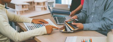 Mimar takımı iç tasarım hakkında renk paleti kullanarak tartışır. Profesyonel iç mimar, toplantı masasına yerleştirilmiş ev modeli olan müşteriye uygun rengi sunar. Değiştirilmiş.