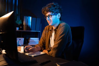 Genç işadamı, Neon Light Modern Ofis 'te yaratıcı bir başlangıç projesi için bilgisayara odaklanıyor. Düşünüyorum da, pazarlama ağı yaratıcıdan pazar kanalı tasarım konseptine çevrimiçi planlama. Toplayıcı.