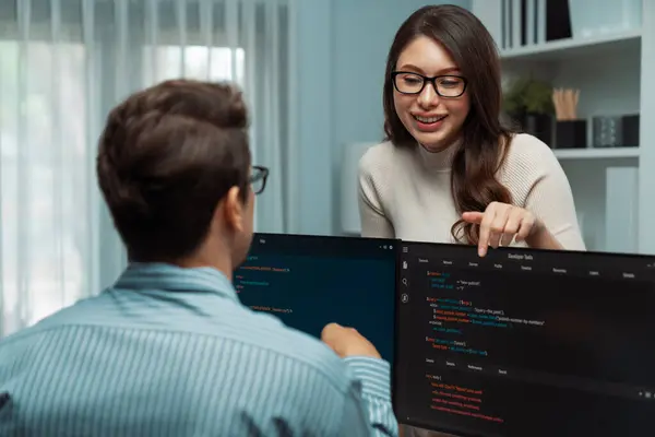 2つのPc画面でコーディングウェブサイトのソフトウェアシステムプロジェクトを議論するために机上で作業する男のプログラマとは対照的に立っている女性の同僚は 完全なスタックデータプロンプト設計をタイプすることと比較します ポストレート — ストック写真