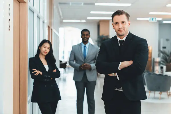 Professional businessman standing with arm folded while coworker stand behind. Group of diverse business people looking at camera with confident. Represent teamwork, working together. Ornamented.