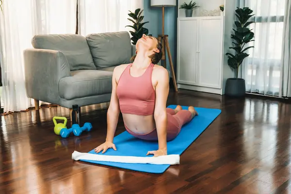 自宅での運動マットの瞑想姿勢でヨガ姿勢をしているスポーツウェアの柔軟でデクスタリティの女性 穏やかな心と静けさで健康的なヨガライフスタイル — ストック写真