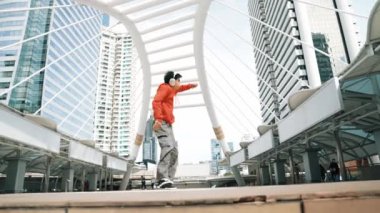 Şehre atlarken kulaklık takan Asyalı hippi. Profesyonel break dansçı şehirde break dans gösterisi yapıyor. Break dans ya da sokak dansı. Açık hava sporu 2024. Yumuşak bir şekilde..