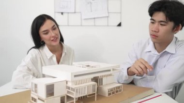 Profesyonel akıllı iş birliği mühendisi mühendis ekibi modern ofisteki ev yapısını planla kontrol ederken genç ve güzel proje yöneticisi not alıyor. Yaratıcı tasarım konsepti. Tertemiz...