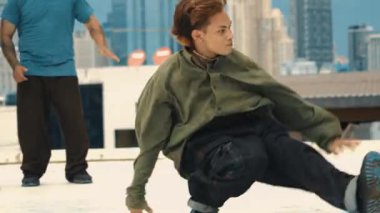 Profesyonel Asyalı sokak dansçısı çatıda çok kültürlü arkadaşlar dans ederken B boy dansı yapıyor. Genç modern dans grubu hip hop hareketi yapıyor. Tarz, moda, aksiyon. Açık hava sporu 2024 hiphop..