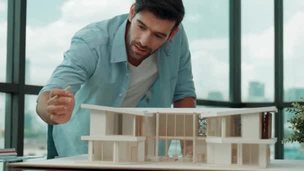 英俊的高加索工程师或项目经理站在城市的全景窗前 俯瞰摩天大楼时 会检查 查看房屋模型并在蓝图上写字 小道消息 — 图库视频影像