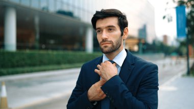 İş adamının portresi yolda yürürken kravatı ayarlar. Yönetici şehre bakarken takım elbise giyiyor. Yatırımcı görüşmeye gitmeden önce kendini kontrol etmiş. Arka plan bulanık. Sevinçli..