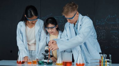 Zeki kız deney yapmak için heyecanlanan çeşitli öğrenciler iken beher kabına renkli solüsyon döker. Profesyonel bilim adamı kimyasal teoriyle kara tahtada deney yapmaya hazırlanıyor. Öğretim.