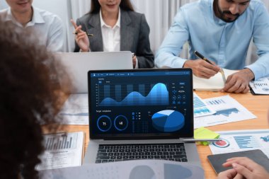 Çok ırklı analist ekibi toplantı masasındaki finansal verileri analiz etmek için BI Fintech yazılımı kullanıyor. Finansal konsol veri ekranında pazarlama göstergesi için analiz edilmiş grafikle birlikte. Uyum