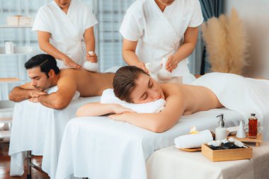 Sıcak bitkisel top spa masaj vücut tedavisi, masör nazikçe bitki torbasını çift müşteri vücuduna bastırıyor. Aromaterapi dinlenme sükuneti ve sükuneti kaplıca salonundaki atmosferi aydınlatıyor. Sessiz.