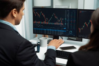 Dinamik borsada döviz kuru yatırımını tartışan iki ticaret simsarı iki bilgisayar ekranında gerçek zamanlı risk grafiği ya da modern ofisteki kar noktasını karşılaştırıyor. Varsayım.