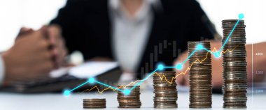 Dijital grafik göstergeli bozuk para yığını iş yatırımını ve ekonomik büyümeyi sembolize ediyor. Finansal hedefe ulaşmak ve kâr sağlamak için finansal planlama yapan bir iş adamı. Kurnaz.