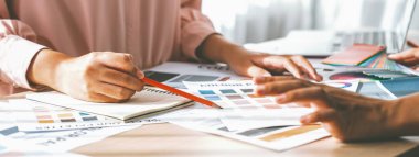 Profesyonel iç mimarların kırpılmış görüntüsü proje masasında renk paleti dağılımı ile ana tema rengini tartışır ve beyin fırtınası yapar. Yaratıcı iç tasarım konsepti. Değiştirilmiş.