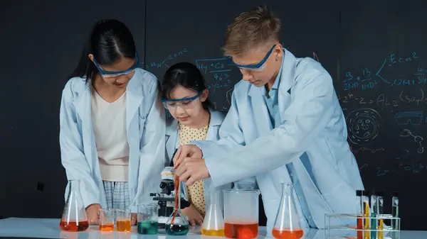 Menina Inteligente Derramar Solução Colorida Para Copo Enquanto Estudante Diverso — Fotografia de Stock