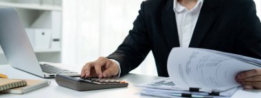 Şirket muhasebecisi, mali veri raporuna dayanarak vergi iadelerini hesaplamak ve en yüksek seviyeye çıkarmak ve finansal performansı artırmak için hesap makinesi kullanır. Panorama 'daki modern muhasebe. Kurnaz.