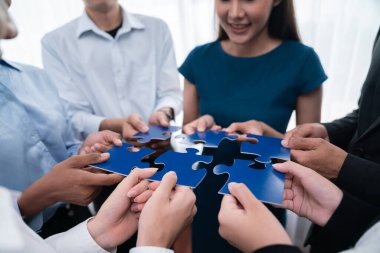 Çeşitli şirket çalışanları, ortaklık ve takım çalışmasını temsil etmek için bulmaca parçalarını birleştirerek ofiste işbirliği yapıyor. Yapboz 'u birleştirerek iş dünyasındaki birlik ve sinerji. Uyum