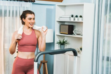 Spor ve atletik bir kadın, evdeki fiziğe ve sağlıklı spor yaşam tarzına uygun vücut egzersizi sırasında koşu bandında koşuyor. Gaiety evde egzersiz eğitimi.