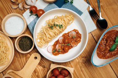 Lezzetli yiyecekler, ev yapımı spagetti, kıymalı domates sosu ve fesleğen fırlatma elementleri, şef masası dekoratif baharatlarla servis ediliyor. Varsayım.