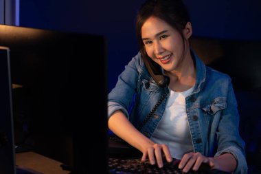 Gülümseyen güzel Asyalı yaratıcı kadın telefon masasından müşteriye ya da iş arkadaşına arıyor yaratıcının projelerini açıklarken geceleri neon ofisteki pazar analizini araştırıyor. Taktik.