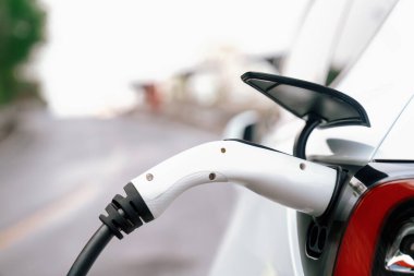 Kapalı EV şarj kolu fişe takıldı veya elektrikli arabaya bağlandı, EV araba aküsünü temiz çevre için sıfır CO2 emisyonu ile alternatif ve sürdürülebilir enerjiyle şarj etti. Kalıcı