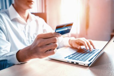 Genç adam, laptop bilgisayar başvurusu ya da web sitesinde online alışveriş yapmak için kredi kartı kullanıyor. E-ticaret ve online alışveriş konsepti. uds