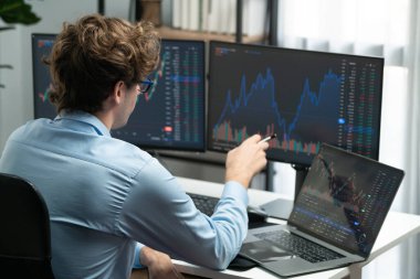 Piyasa stoku grafiği üzerinde çalışan genç profesyonel tüccar ev ofisindeki gerçek zamanlı ekranlara yatırım yaparak önemli döviz kuru kavramları yazarak analiz ediyor. Toplayıcı.