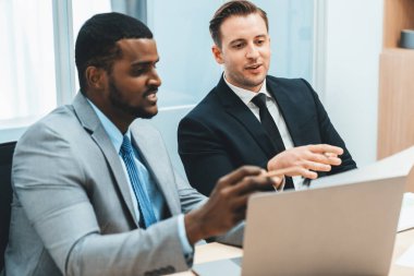 Afrikalı erkek lider stratejiyi açıklarken profesyonel proje yöneticisine çözümünü dizüstü bilgisayar kullanarak belgeye işaret ederek gösteriyor. Yetenekli iş adamlarının beyin fırtınası fikri. İş toplantısı. Süslü.