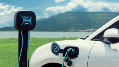 Elektrikli araba şarj istasyonuna bağlanır, EV şarj kablosu ile pili şarj edilir doğası gereği akıllı dijital batarya durum hologramı görüntülenir. Geleceğin yeşil enerji altyapısı. İnceleyin