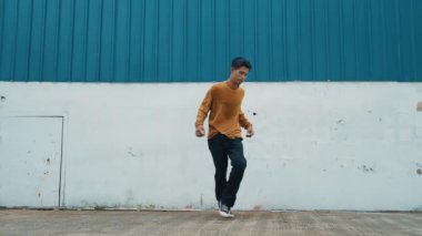 İspanyol adam kollarını açıp duvarın önünde dans ediyor. Dansçı ya da koreografın günlük kıyafetleriyle hip hop tarzında break dans yaparken ki görüntüsü. Açık hava sporu 2024 hiphop..