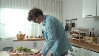Mutlu baba yemek pişirirken müziğe geçiyor ve modern mutfakta öğle yemeği hazırlıyor. Aktif baba, sebze ve mutfak gereçleri ile çevrili sağlıklı yemek ya da salata yaparken şarkıyla dans ediyor. Pedagoji.