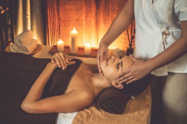 Beyaz kadın stres önleyici kafa masajı yapmaktan ve lüks otel veya otelde sıcak mum ışığında yüz güzelliği eğlencesi yapmaktan zevk alıyor. Sessiz.