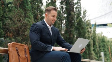 Green City 'de otururken bilgisayarla çalışan iş adamlarının yan görüntüsü. Akıllı yönetici bilgisayar yazma raporunu ve pazarlama stratejisini uzaktan kumandayla iş ekibiyle çalışırken kullanıyor. Urbane.