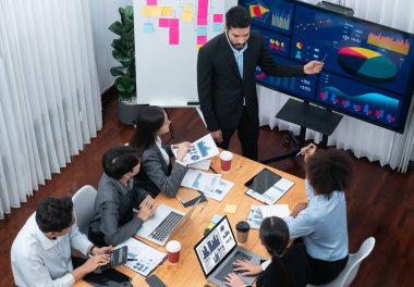 Modern toplantı odasındaki TV ekranında veri analizi paneliyle üst görünüm iş sunumu. İş adamlarının iş pazarlama stratejisini planlamak için beyin fırtınası yapması ya da birlikte çalışması. Uyum
