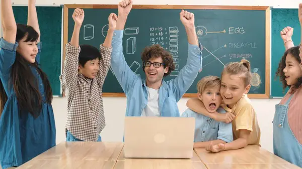 成功したプロジェクトを祝い 空中に手を置いている間 教師と多文化の学生 教室の黒板に立っている間 カメラに微笑む子供たちのグループ ペダゴロジー — ストック写真