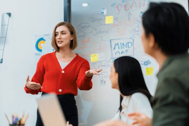 Kafkasyalı genç bir iş kadını, pazarlama stratejisini zihin haritası kullanarak sunuyor, soruları kendinden emin bir şekilde cevaplarken grafiğini çiziyor. Takım çalışması, beyin fırtınası, tartışma konsepti. Tertemiz..