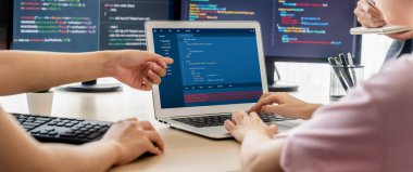 Bilgisayar ekranında program kodu gösterilirken iki akıllı kooperatif bilgisayar mühendisi program kodunu çözmek için takım çalışması yapıyor. Laptop, web geliştirme, programcı, Java betiği. Filizlenen.