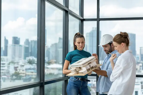 Smart engineer holds house model and explain about house construction to skilled manager. Group of interior designer inspect architectural model. Working together, Civil engineering. Tracery.